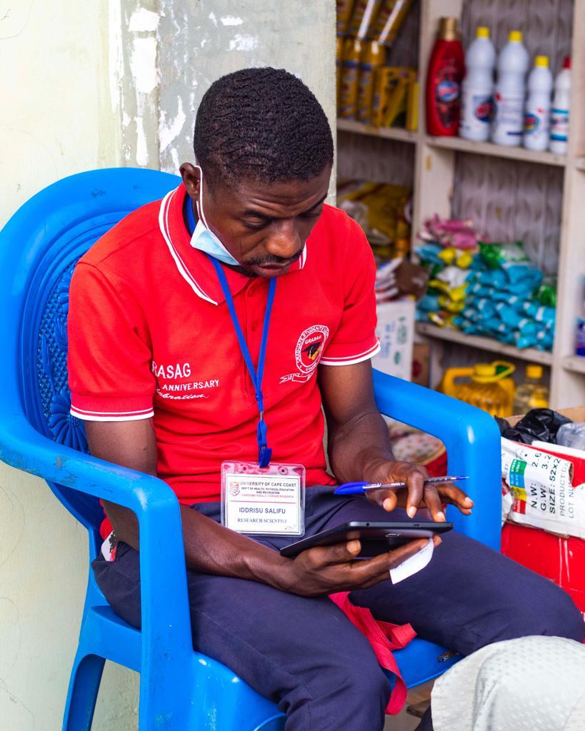 A research scientist recording data on a tablet during a community visit